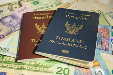 Thai citizen passport and Thai Official passport with Banknotes of Different countries, preparing to travel.の写真素材