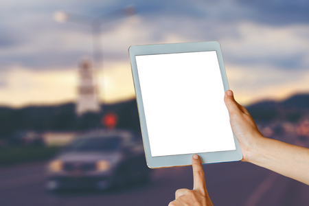 woman hand hold and touch screen tablet over the street in the eveningの写真素材