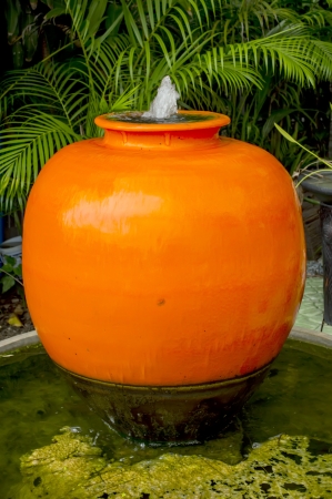 orange fountain jar in green gardenの写真素材