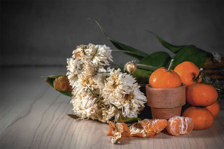 white mums and small orange on wood texture still life photoの写真素材