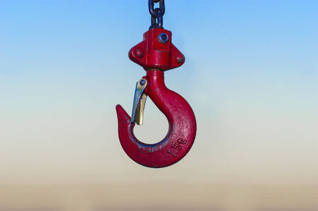 red Industrial hook hanging on reel chain and blue sky sunset backgroundの写真素材