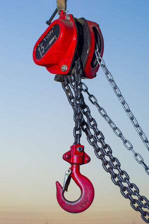red Industrial hook hanging on reel chain and blue sky sunset backgroundの写真素材