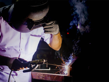 welder working with protective mask welding metal and sparks