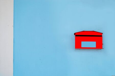 red mailbox on blue and white concrete wall