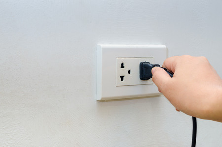 hand outlet Power saving Hand inserting electrical plug into outletの写真素材