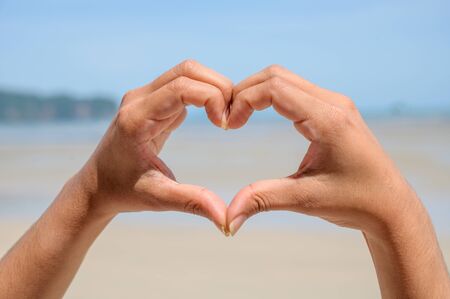 The hands of women and men are the heart shape with the sun light passing through the handsの写真素材