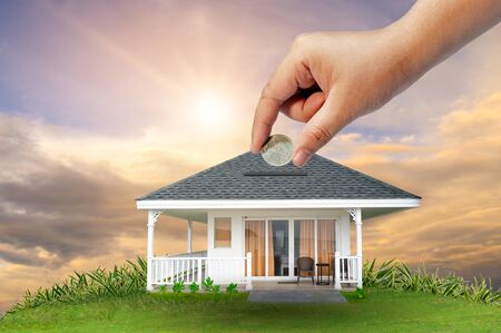 The hands of a businessman hold money and the other hand holds a house. The idea of saving money to buy a houseの写真素材