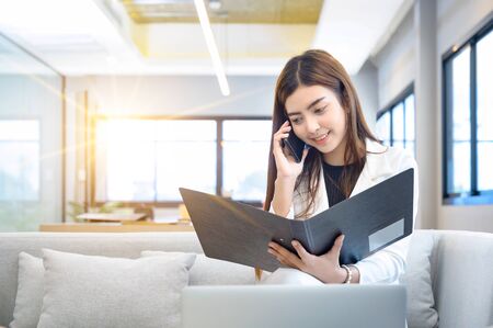 Business women holding files and talking on the phoneの写真素材