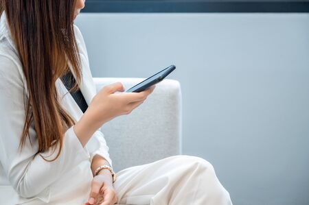 Business women wear white clothes glad to play mobile phone in a white backgroundの写真素材