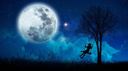 imagination The girls are cradling amidst many stars and full moon at night.の写真素材