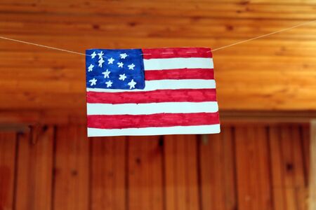 American flag hanging on threads against the background of wooden ceiling