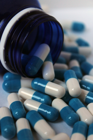 Blue and blue tablets in a and around a jar of medicineの写真素材