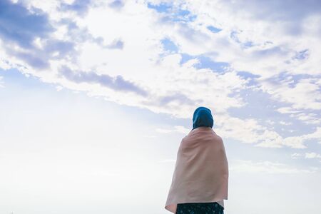 Muslim woman in a headscarf against the sky with cloudsの写真素材