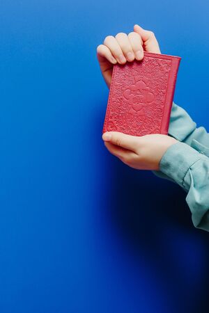 Muslim woman in a headscarf holds a Quran in her hands on a pink backgroundの写真素材