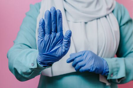 Muslim girl in a tent in medical gloves shows a stop signの写真素材