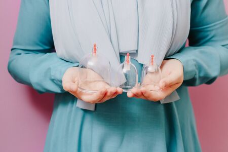 A girl in a scarf holds in her hands jars for hijama. Vacuum pumps Droppingの写真素材