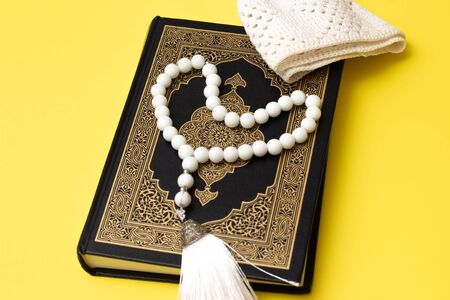 Quran white rosary and skullcap on a yellow backgroundの写真素材