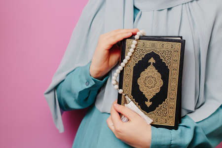Muslim girl holding quran and islamic rosary in her hands