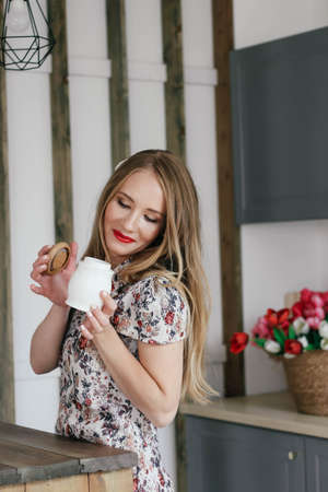 Blonde girl with a sugar bowl in her hands. In the background are tulips.の写真素材