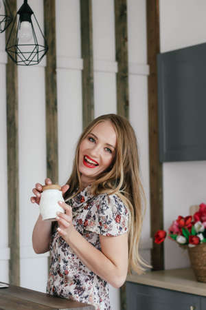 Blonde girl with a sugar bowl in her hands. In the background are tulips.の写真素材