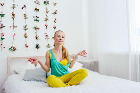 Blonde girl meditates on the bedの写真素材