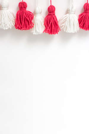 brushes from yarn of red and white color on a white background. Space for copy space. DIY yarn brushes. Garland Garland of yarn. Pampushki from yarn. Children's creativityの写真素材