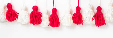 brushes from yarn of red and white color on a white background. DIY yarn brushes. Garland Garland of...