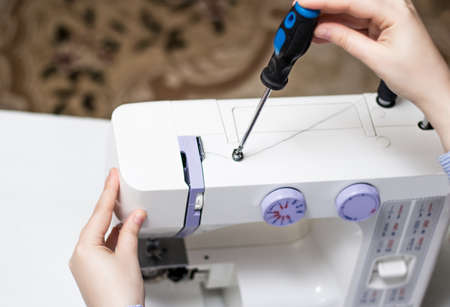 Sewing machine repair. Screwdriver. White sewing machine. Sewing content. Repair of household...