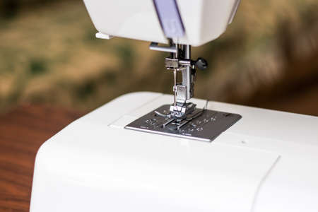 Close up view of sewing process. Professional manufacturing machine at workplace. Needle of the sewing machine. Light blurred background.の写真素材