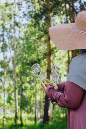 The girl holds in her hands jars for hijama and a pump. Bloodletting. Muslim hijam. The doctor who does the bloodletting. Flowers Sunnah treatment. Muslim girl in a pink dress. Hijab.の写真素材