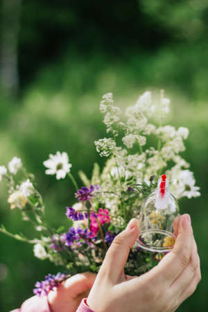 The girl is holding a jar for hijama. Hijama, bloodletting, treatment of sunna. Jars for bloodletting against the background of trees and greenery.の写真素材