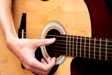 The guy plays the guitar. Close plan. Wooden guitar.
