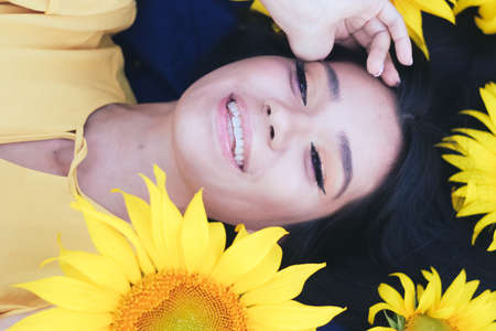 A brunette woman in a yellow dress on the field with sunflowers. Orange dress. Close plan. Butey....