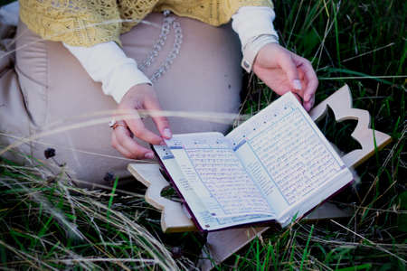 A Muslim woman in the field reads the holy book of the Koran.の写真素材