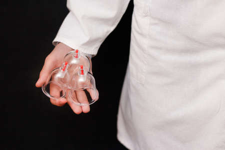 Jars for hijama bloodletting in the hands of a doctor in a white coat on a black background. Hijama according to the Sunnah. Hajjamの写真素材
