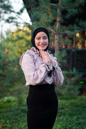 Muslim woman in hijab on the background of trees. Pink blouse and black skirt. Beautiful young woman.の写真素材