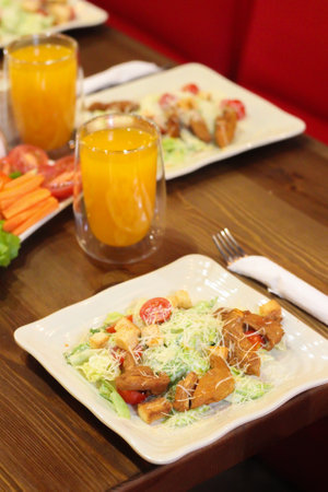 Caesar salad in the restaurant and orange juice. Caesar salad with chicken.の写真素材