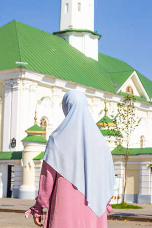 Muslim woman in pink dress on the background of the mosque. Blue scarf.の写真素材