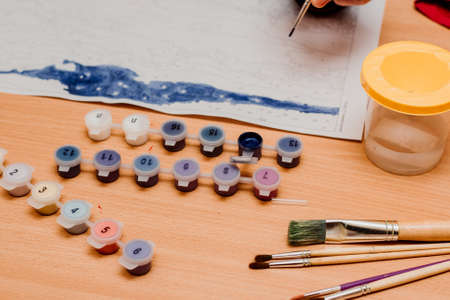 The guy paints a picture by numbers. Watercolor paints. Painting brush, Painting by numbers conceptの写真素材