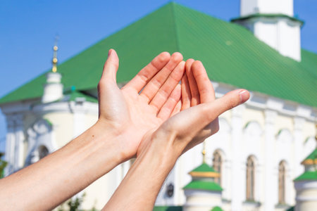 Hands raised in prayer. Muslim man praying on the background of the mosque.の写真素材