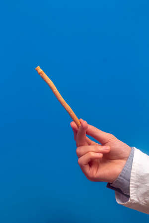 Guy hold miswak on blue background. Teeth cleaning. Sunnah teeth brushing. Sivak.の写真素材
