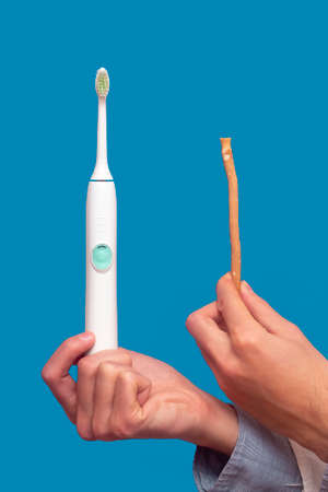A guy in a white coat holds a white electric toothbrush and miswak (sivak), arak tree, Persian Salvador. Dental hygiene.の写真素材