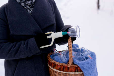 A woman in a gray coat holds a basket of hijama cans. Hijama jars and hijama pump, bloodletting, Chinese medicine.の写真素材