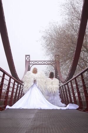 Two girls in angel costumes and white dresses walkingの写真素材