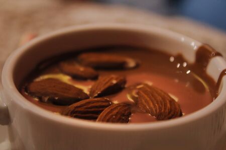 A close up of a coffee cup on a plate with almondの写真素材