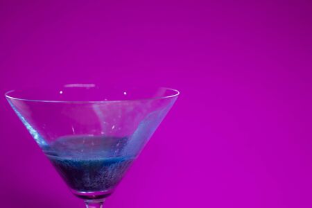 blue liquid in a cocktail martini glass on a pink backgroundの写真素材