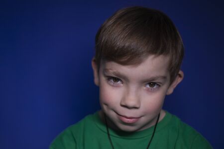 portrait of a nine year old blond boy on a blue background - horizontal photoの写真素材