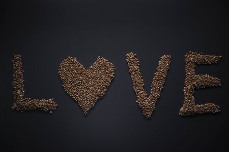 Words LOVE written with buckwheat On gray background, top view, copy space. Food supplies crisis, food donation on quarantine isolation period.の写真素材