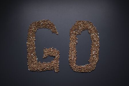 Word GO written with buckwheat On gray background, top view, copy space. Food supplies crisis, food donation on quarantine isolation period.の写真素材