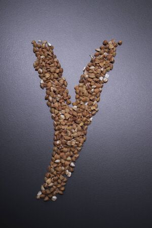 Letter y written with buckwheat On gray background, top view, copy space. Food supplies crisis, food donation on quarantine isolation periodの写真素材